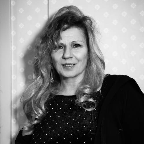 En svartvit bild på en kvinna som står mot en inomhusvägg
